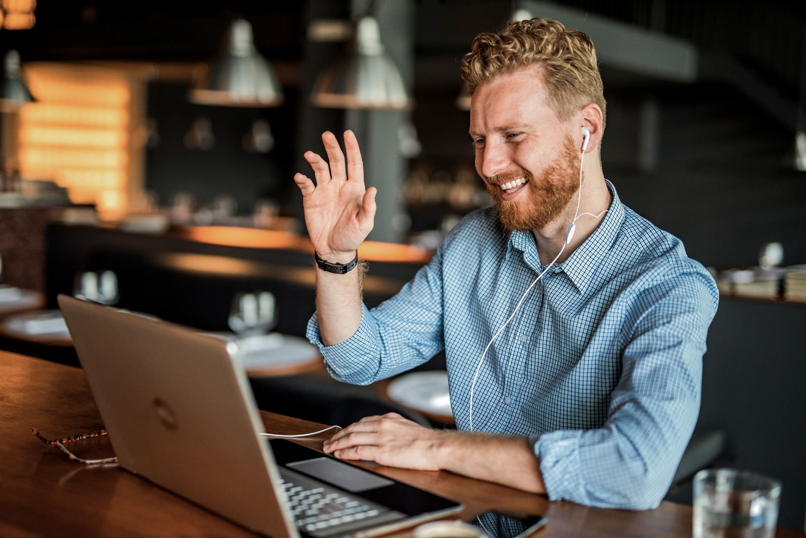 Happy young businessman waving to an online client.
